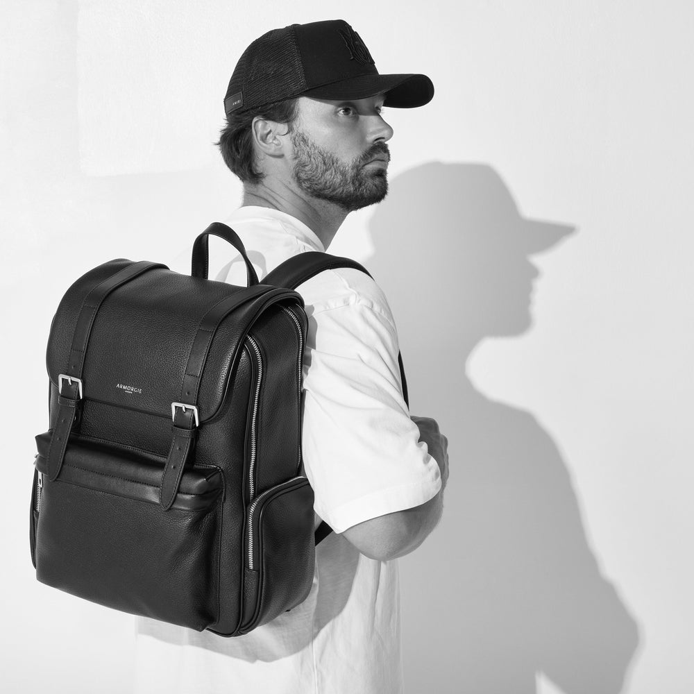 Man wearing a black backpack against a white background